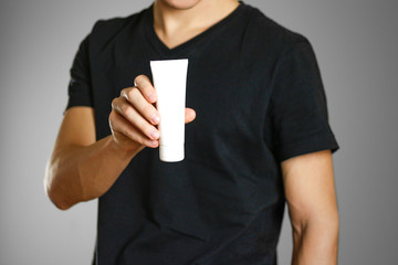 The guy is holding in his hand a bottle of white cream