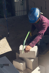 Construction concept, Bricklayer worker installing wite blocks to build wall at construction site