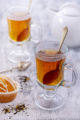 Glass cup of tea on white table with cupcake