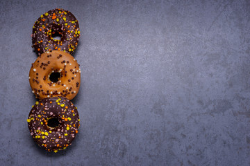 Colorful donuts with chocolate on stone table