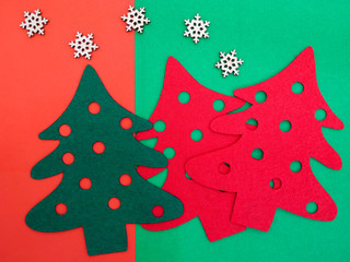 Fototapeta na wymiar red and green felt pine trees and some wooden snowflakes
