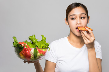 Young woman holding salad bowl and pizza.