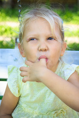 little blonde girl eats peanut butter by her finger