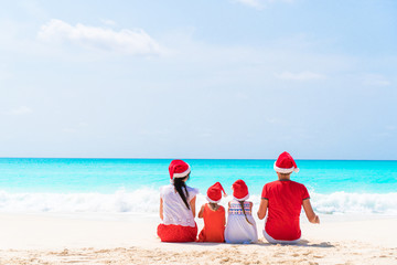 Happy beautiful family in red Santa hats on a tropical beach celebrating Christmas © travnikovstudio