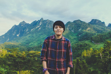 Naklejka premium Asian young man in Scottish shirt and black hat hiking at mountain peak above clouds and fog Hiker outdoor. Doi Luang Chiang Dao Chiangmai Province,In morning.