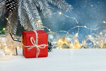 glowing retro light garlands, gift box and blurred christmas tree silver branch on blue background