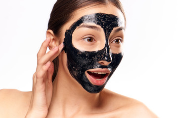 Woman on white isolated background, black coal cosmetic face mask