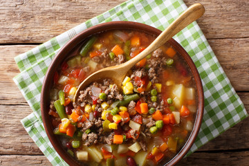 hamburger soup with ground beef and vegetables close-up in a bowl. Horizontal top view