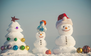 Snowmen with smiley faces in hats on winter day