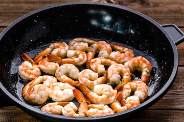 Fried shrimp with garlic on pan, preparing dish with seafood, mediterranean cuisine concept