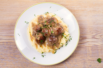 Meatballs with mushroom gravy and mashed potato on white plate. View from above, top studio shot, horizontal