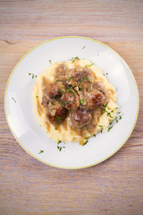 Meatballs with mushroom gravy and mashed potato on white plate. View from above, top studio shot, vertical