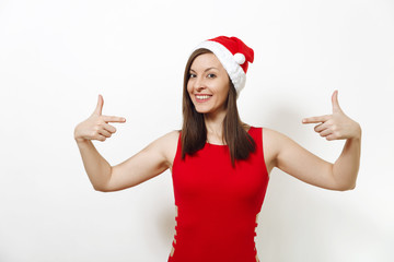 European happy woman wearing red dress and Christmas hat holding copy space between index fingers for advertisement or text on white background. Santa girl isolated. New Year holiday 2018 concept