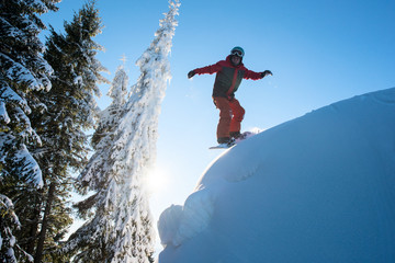 Male snowboarder riding downhill on dangerous slope in the winter mountains copyspace freeride