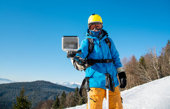 Male skier taking a selfie using his action camera and a selfie stick technology recreation activity in winter ski resort