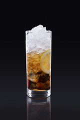 Long island ice tea with lemon ana a lot of ice on black background