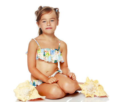 Little girl in a swimsuit with a seashell