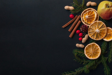 Christmas composition.Noel. tree branches, cinnamon, orange, nuts, Apple on black background. Top view, flat lay.