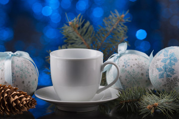 white coffee cup in festive decoration, Christmas toys, blue bokeh background