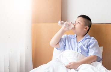 Obese fat boy drinking water on bed in morning