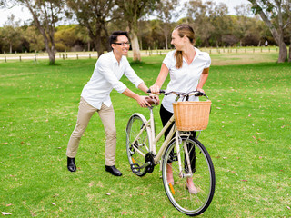 Obraz premium Portrait of smiling couple standing in park with bike talking