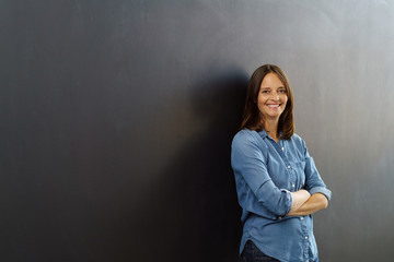 lächelnde frau lehnt an eine schwarzen wand