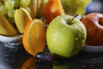 Fresh juicy green apple surrounded by colorful fruits