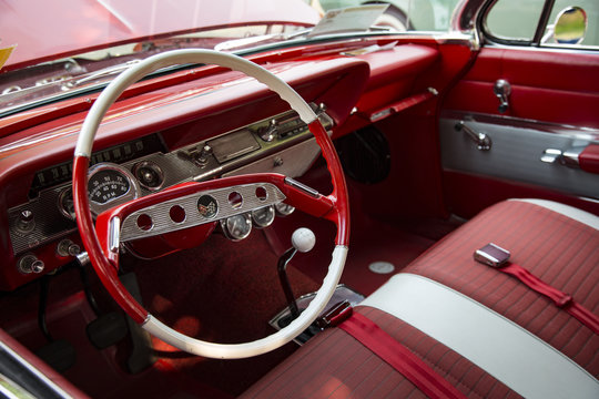 Isolated Interior View of Restored Vintage Automobile with Red Dashboard, Red and White Steering Wheel and Fabric Seats
