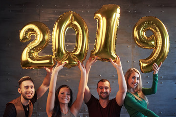 A group of merry young people hold numbers indicating the arrival of a new 2019 year. The party is dedicated to the celebration of the new year. Concepts about youth togetherness lifestyle