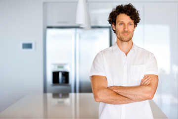 Fototapeta premium Portrait of a smart young man standing in kitchen