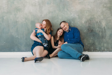 Happy family portrait siting on gray background white floor room sunny day