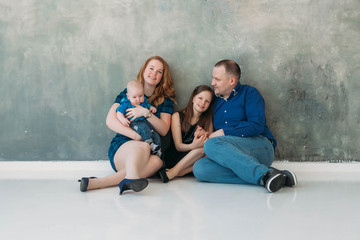 Happy family portrait siting on gray background white floor room sunny day