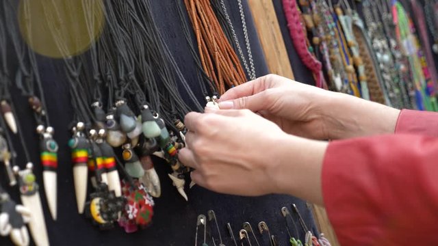 beautiful hippie decoration. the woman looks through the ornaments in the show-window of the street market. 4k, slow motion