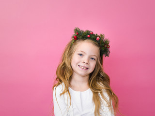 beautiful blond girl with christmas decoration on her head in front of pink background