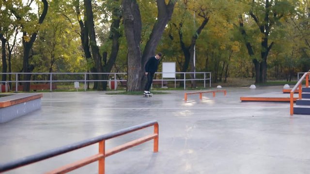Extreme skateboarder grinding down rail, almost falls but jumps on his feet. Slowmotion shot