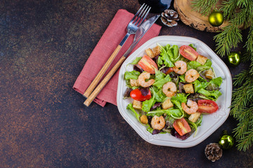 Fresh caesar salad with shrimps on white plate dark stone table background with Christmas Festive Decoration. Healhty Food Snack Concept. Top view Copy Space