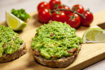 Healthy homemade sandwich with guacamole. Traditionally mexican dish. Lime, tomato, parsley on the background