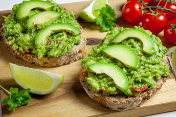 Healthy homemade sandwich with guacamole. Traditionally mexican dish. Lime, tomato, parsley on the background