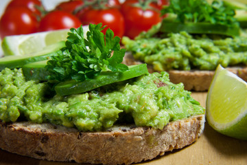 Healthy homemade sandwich with guacamole. Traditionally mexican dish. Lime, tomato, parsley on the background