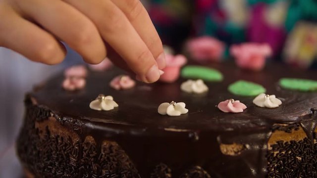 Putting sweet decorations on the home-made chocolate cake that is standing on the swivel base.