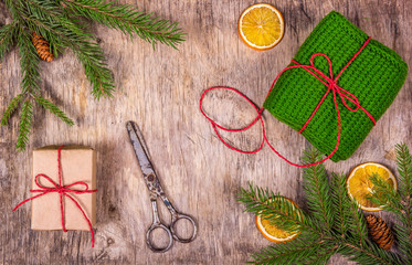 Preparing for Christmas. Packing of gifts. Spruce branches, orange, knitted gift and knives. Grandma's gift.
