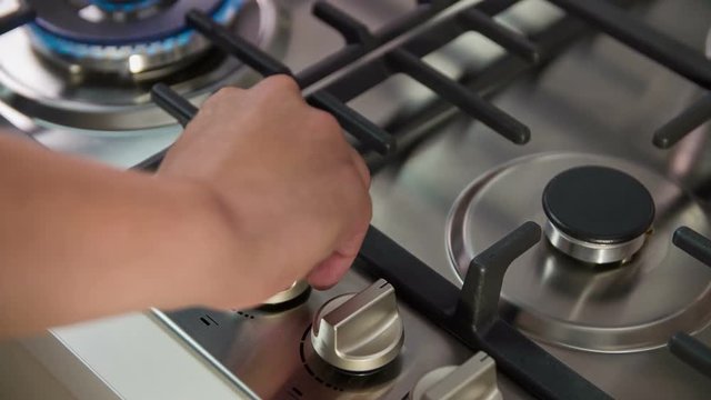 Turning gas on gas stove with automatic electric ignition. The cook puts on a black wok to prepare delicious meal.