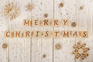 Merry Christmas inscription on cubes on the white wooden background. The view from the top.