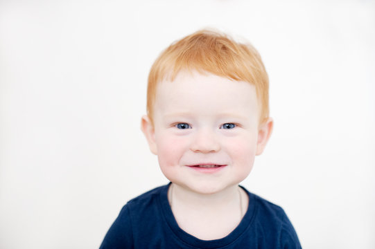 Smiling redhead boy in blue t-shirt on the white background