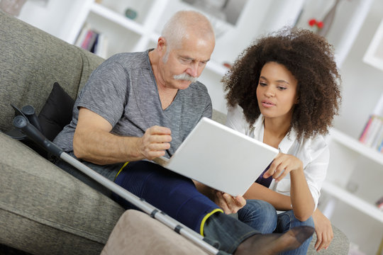young woman helping senior man with a laptop computer