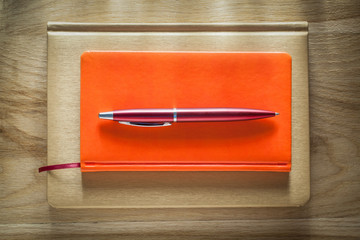 Closed notepads biro pen on wooden board