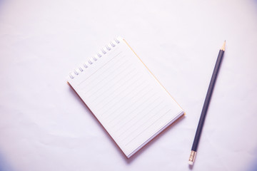 Black pencil and Notebook paper on white background
