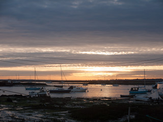 Fototapeta na wymiar sun set sky dramatic clouds sea front beach harbor marina boats moored landscape