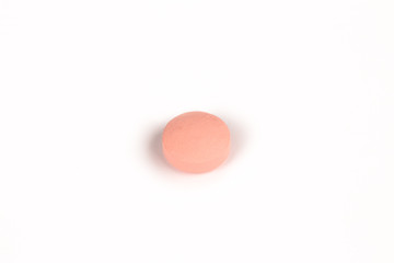 close-up of a salmon pink pill isolated on a white backgound.psd