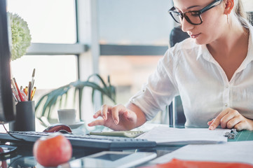 Office worker. Young businesswoman using calculator and laptop for calaulating finance, tax,...